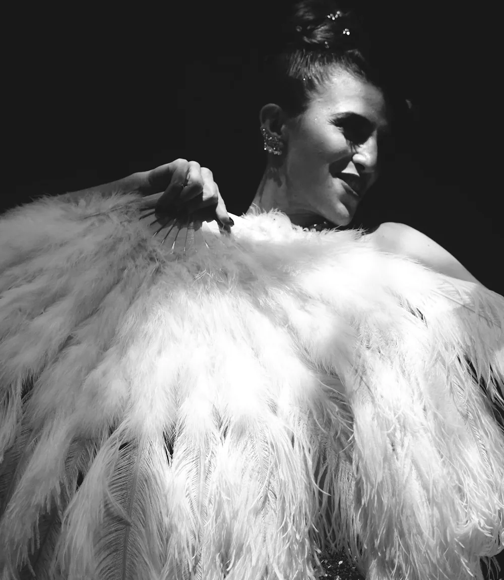 A cabaret performer in an elaborate feathered showgirl headdress